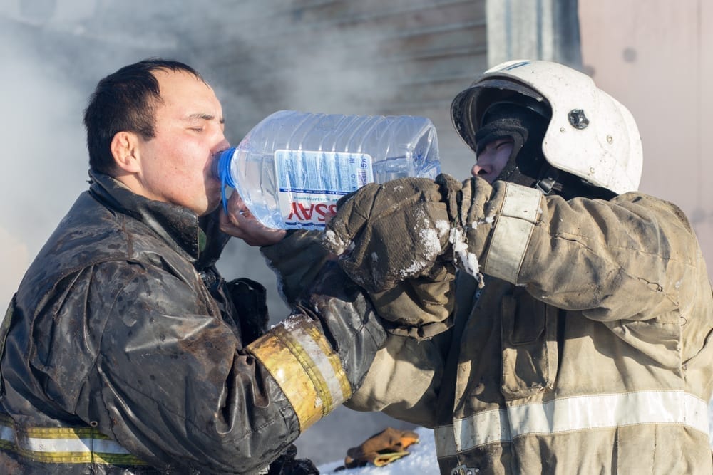 firefighter drinking from jug of water