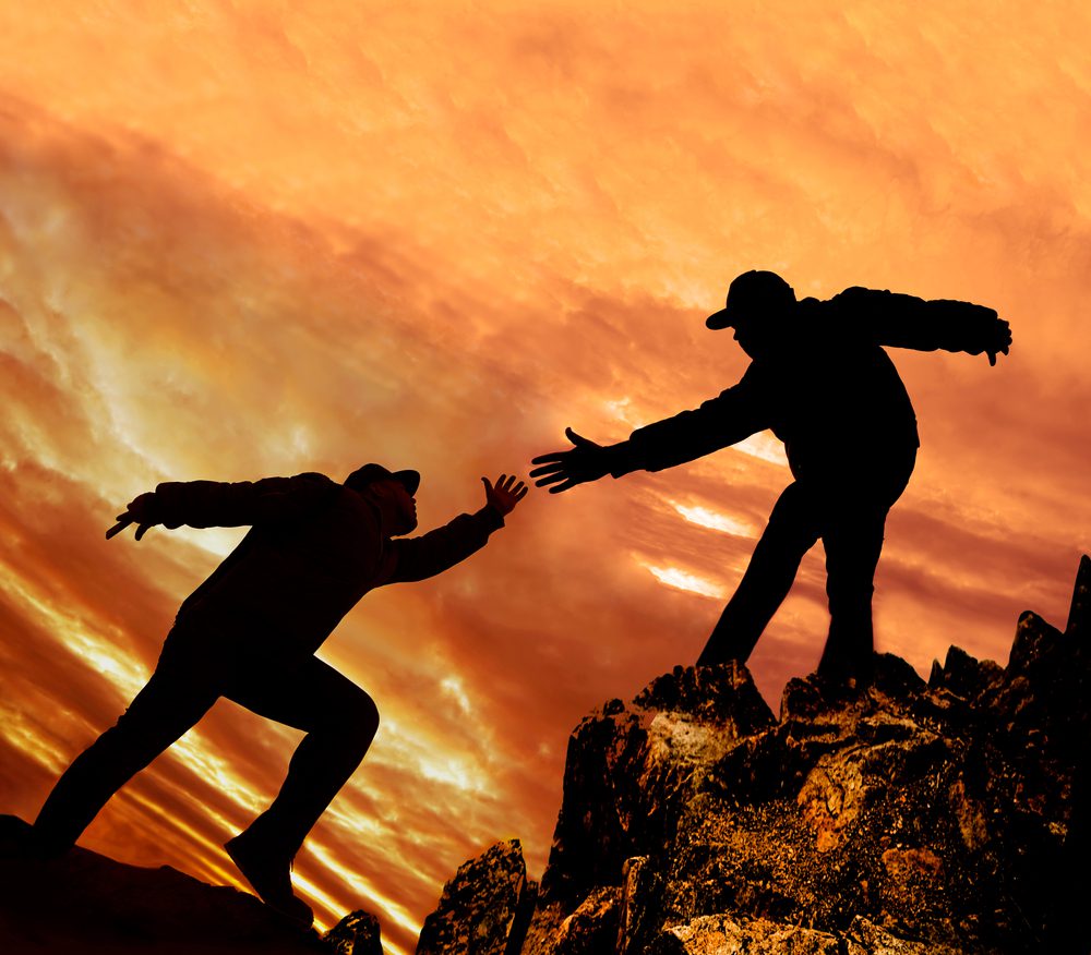 silhouette of a man extending his hand to help another person up