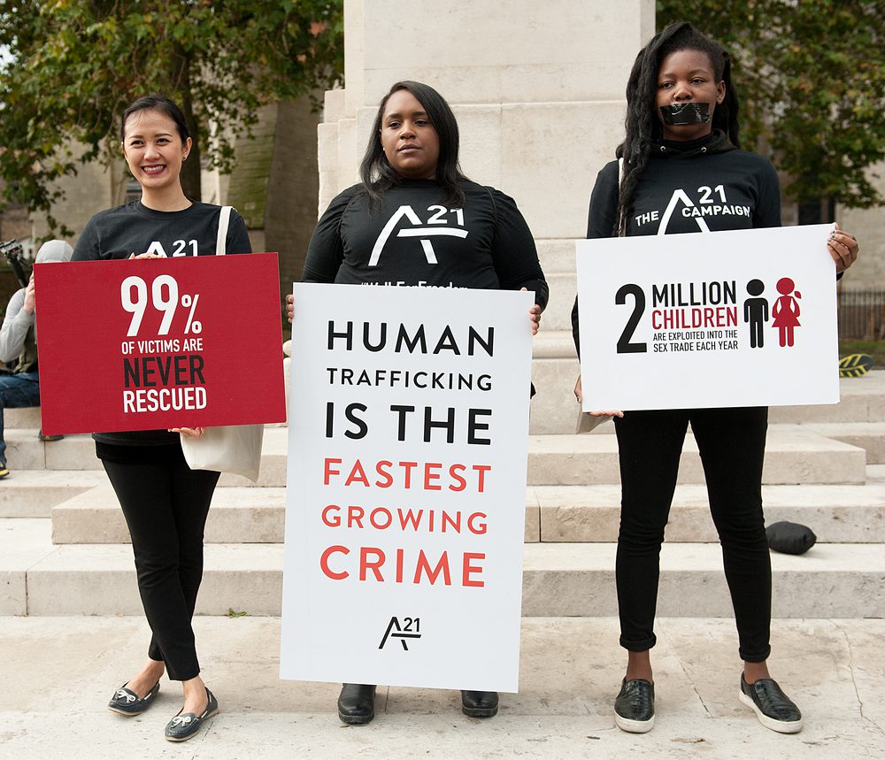 young women holding signs with statistics of human trafficking